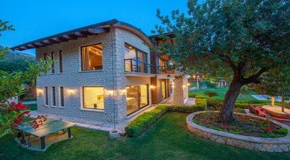 Stone-architecture villa with garden recreation areas at dusk