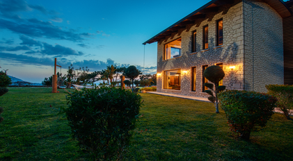 Stone-facade villa overlooking a quiet garden and Mediterranean horizon at dusk