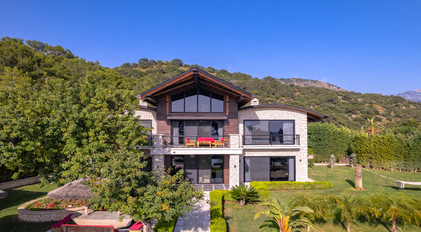 Symmetric front view of Villa Gökçe with stone façade and mountain backdrop