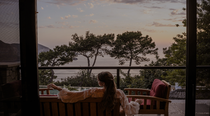 Terrace sunset scene overlooking a quiet Mediterranean bay and pine silhouettes
