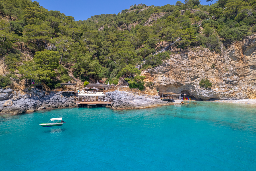 Aerial view of layered waterfront decks beside caves on a turquoise bay