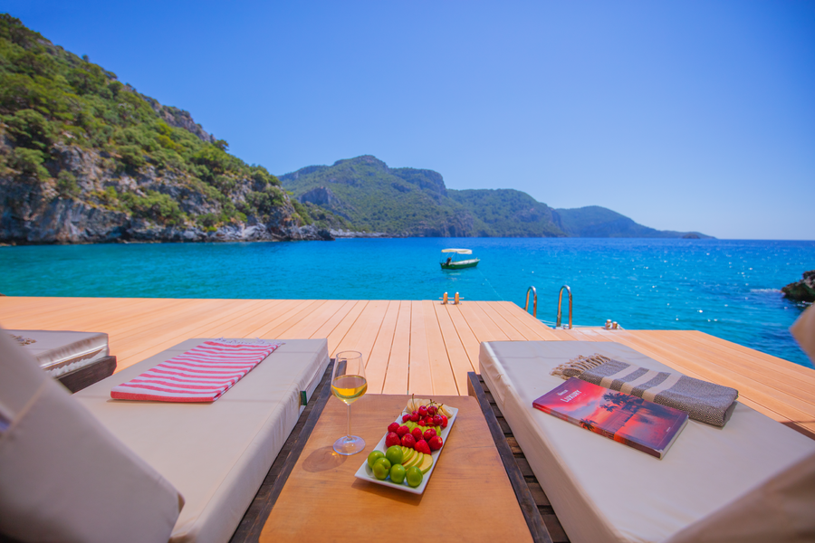 Waterfront loungers facing a tranquil turquoise bay on a wooden deck