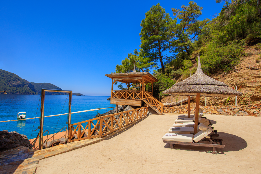 Waterfront Sand Terrace with Shaded Loungers on a Secluded Mediterranean Bay