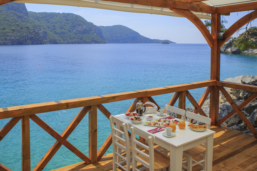 Private chef breakfast table on a wooden terrace overlooking a calm Mediterranean bay