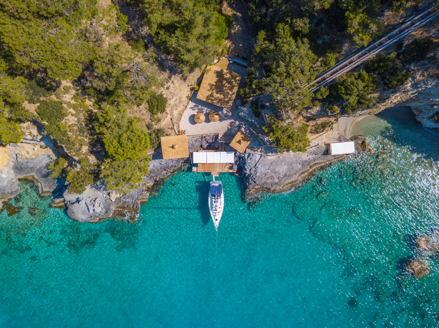 Aerial view of yacht moored at the private landing deck in a turquoise Mediterranean cove