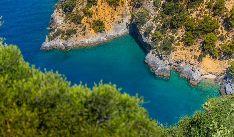 Hidden Mediterranean cove with turquoise water and rugged forested cliffs