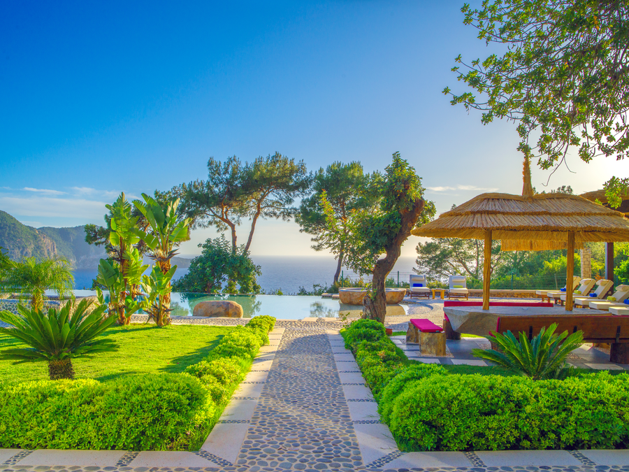Secluded garden pathway leading to an infinity pool with Mediterranean views