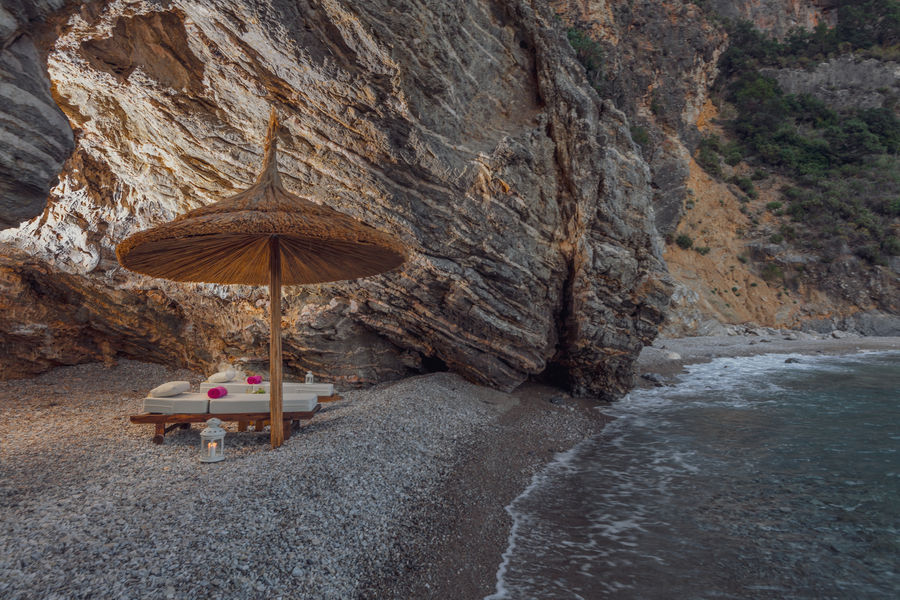Secluded shoreline lounge set beneath dramatic rocky cliffs