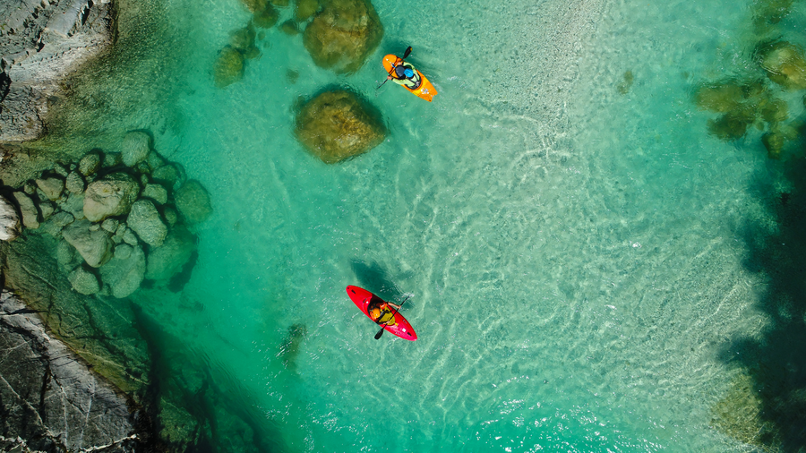 Aerial view of kayakers paddling over crystal-clear turquoise shallows