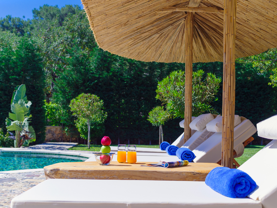 Poolside wellness loungers shaded by bamboo umbrellas in a calm garden