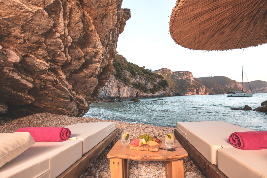 Seaside wellness loungers set within a quiet private cove at sunset