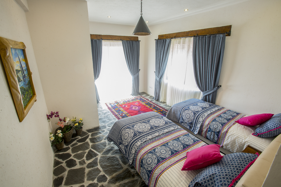 Bright twin bedroom with stone flooring and large sunlit windows