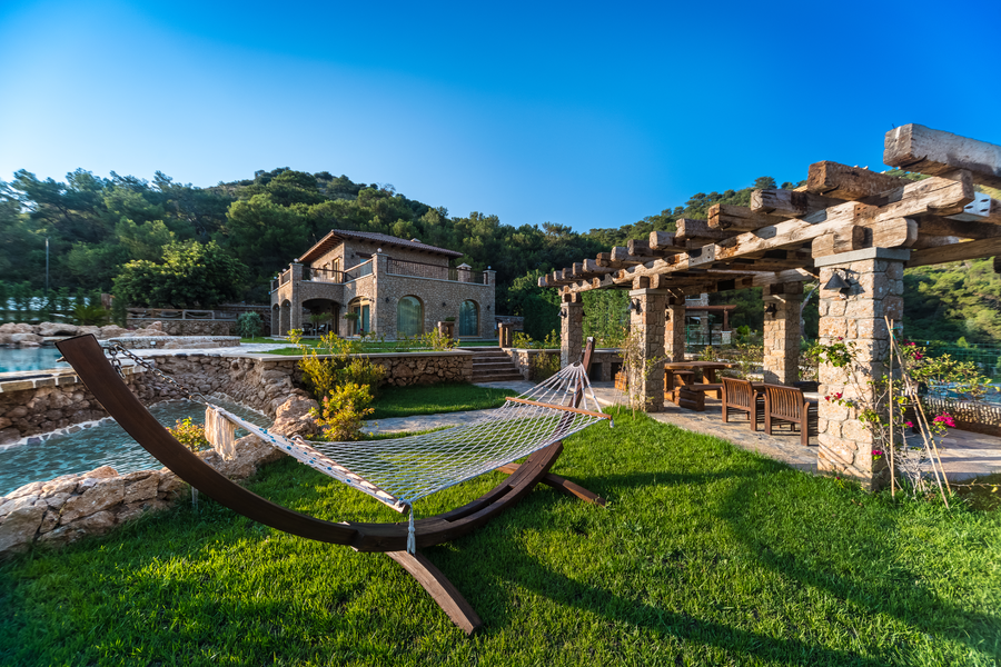 Stone villa with garden hammock and shaded pergola on a forested hillside