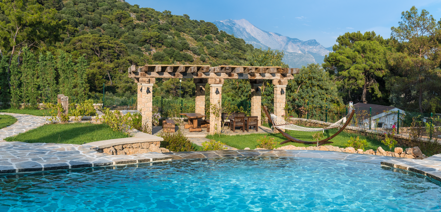 Stone pergola and garden terrace overlooking the pool and mountain forest