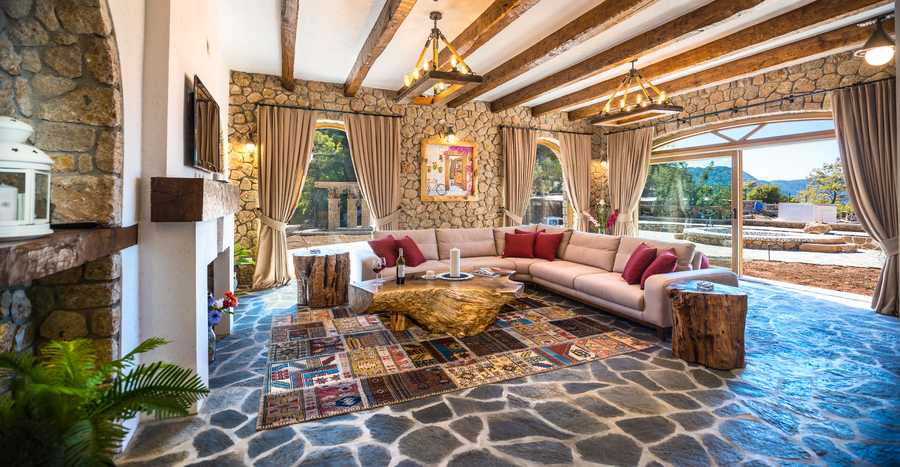 Rustic stone-walled living room with large sectional sofa and wooden beams