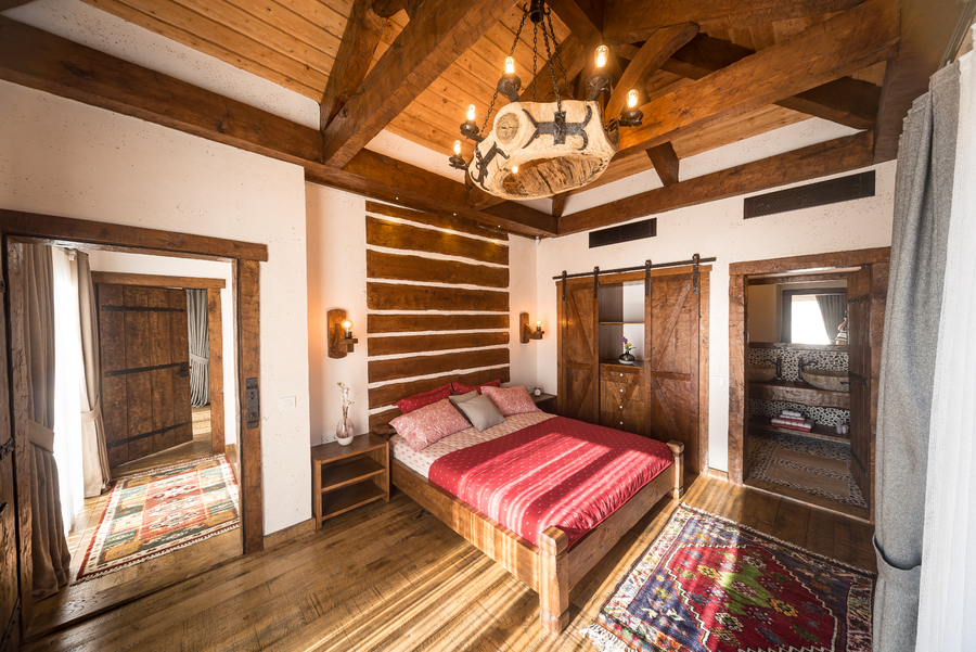 Rustic master bedroom with timber beams, stone accents and warm natural light
