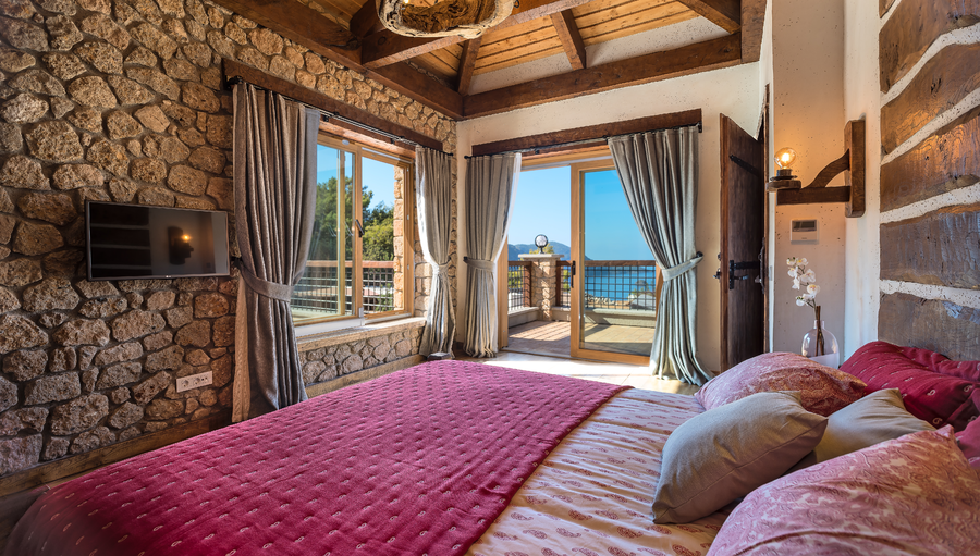 Master bedroom with stone walls and panoramic sea-view terrace