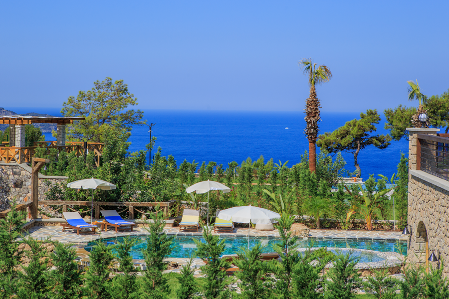 Pool terrace with Mediterranean sea view framed by lush greenery