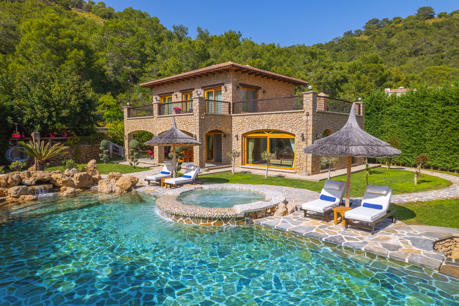 Sunlit poolfront view of Villa Elmalı with stone architecture and jacuzzi