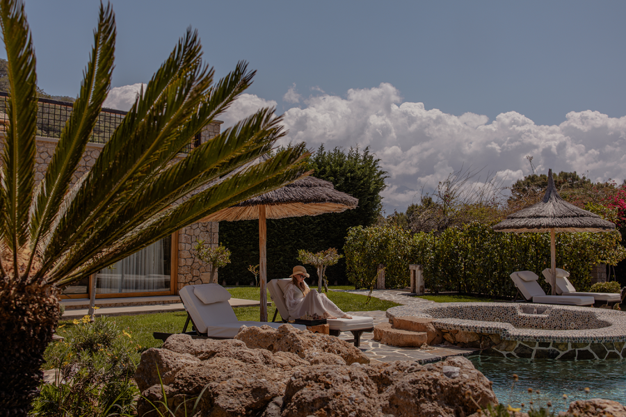 Guest relaxing by the pool under a thatched parasol