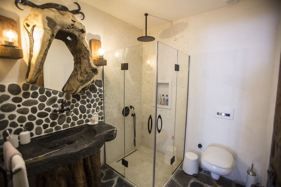 Rustic stone and wood bathroom with glass shower and handcrafted details
