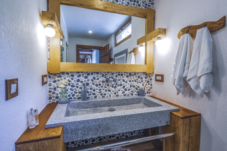 Stone-accent bathroom vanity with handcrafted wooden details and soft Mediterranean light