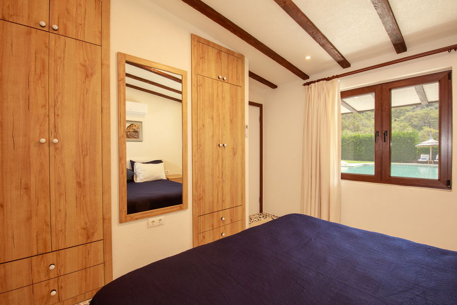Bedroom interior with wooden wardrobes and window overlooking the pool