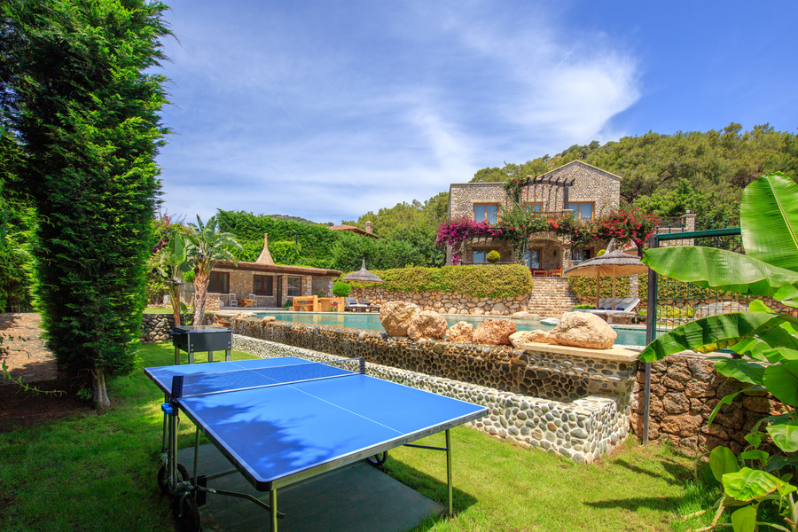 Estate pool and garden area with stone architecture and outdoor ping pong setup