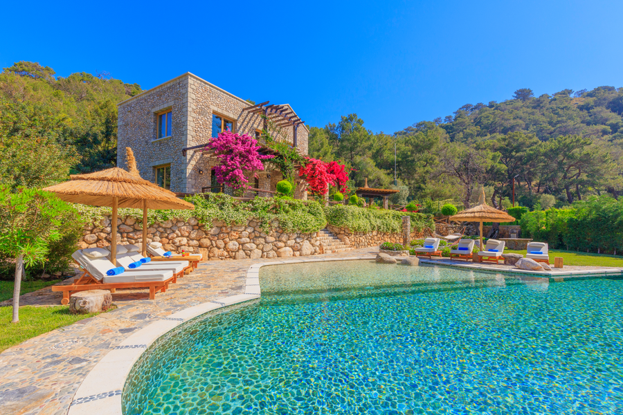 Mediterranean stone villa with natural-style pool and vibrant bougainvillea gardens