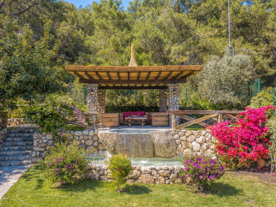 Stone pergola lounge overlooking a tranquil garden corner