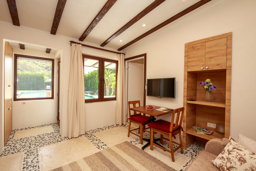 Living area with pool-view windows and stone-detailed Mediterranean flooring