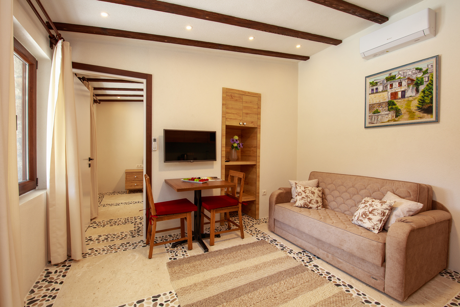 Cozy living-dining space with stone floor details and wooden ceiling beams