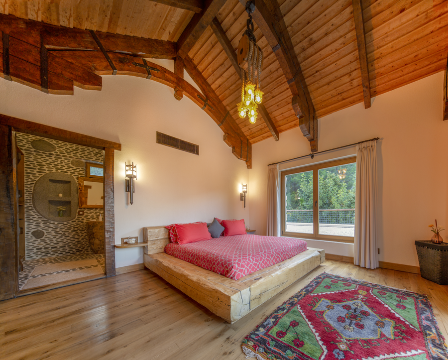 Master bedroom with rustic wood ceiling and stone-detailed ensuite bathroom