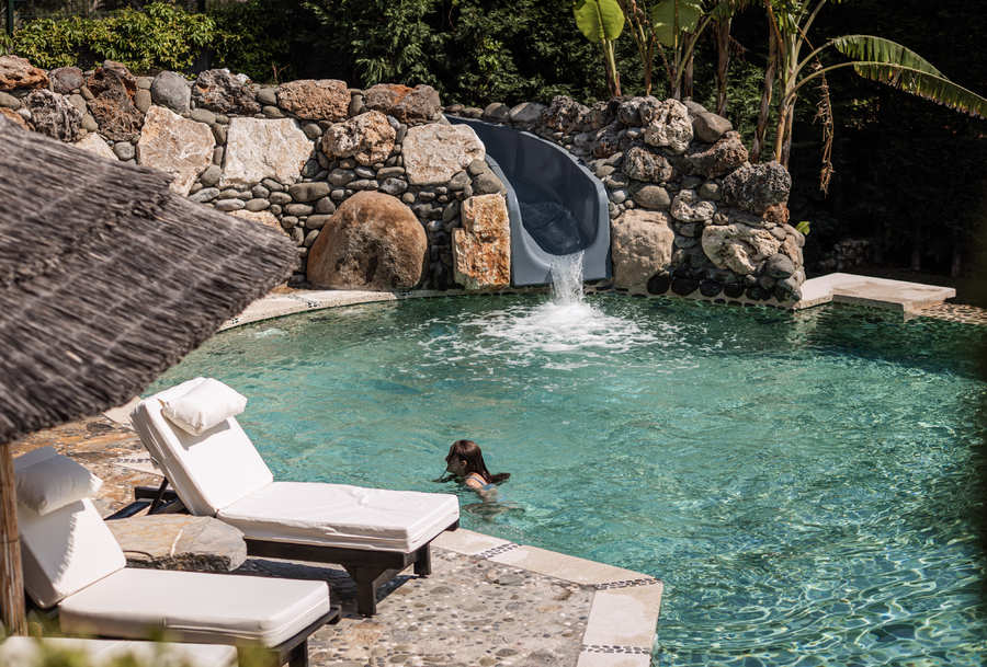 Organic-shaped pool with stone waterslide and Mediterranean surroundings