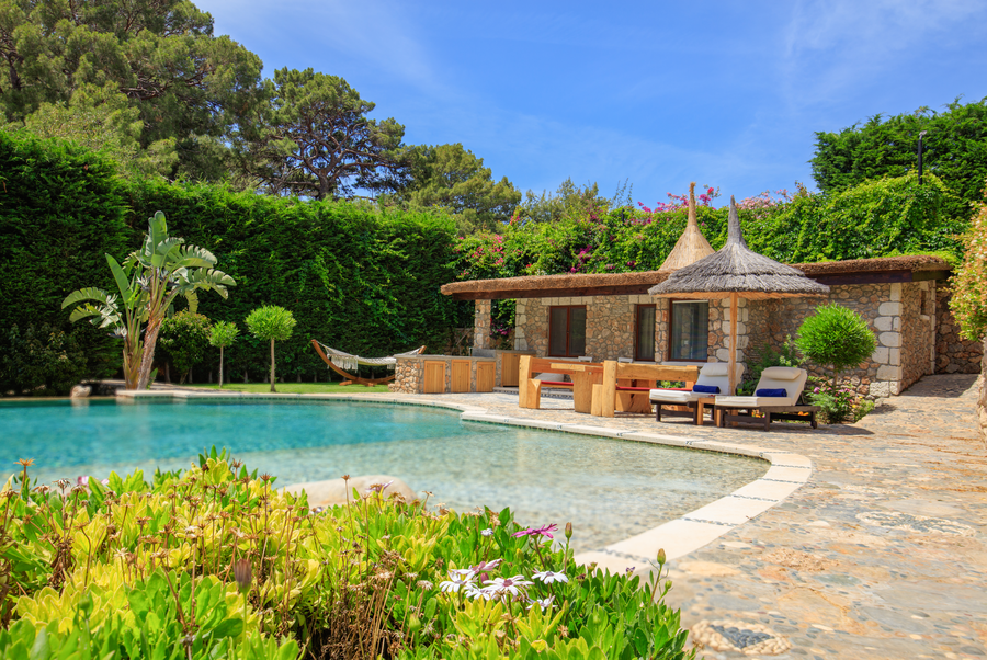 Poolside Mediterranean garden with stone cabana and shaded loungers