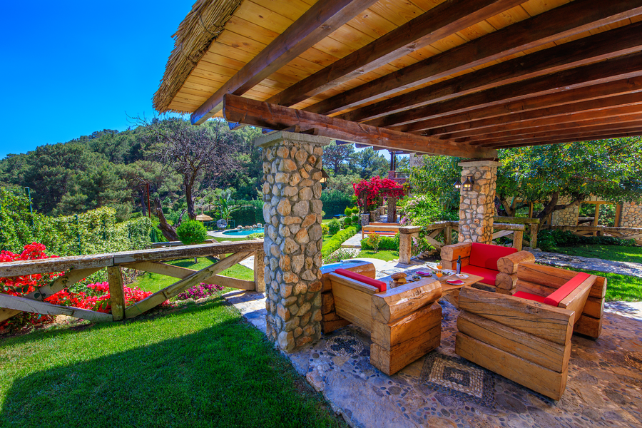 Shaded stone-column lounge overlooking landscaped Mediterranean gardens