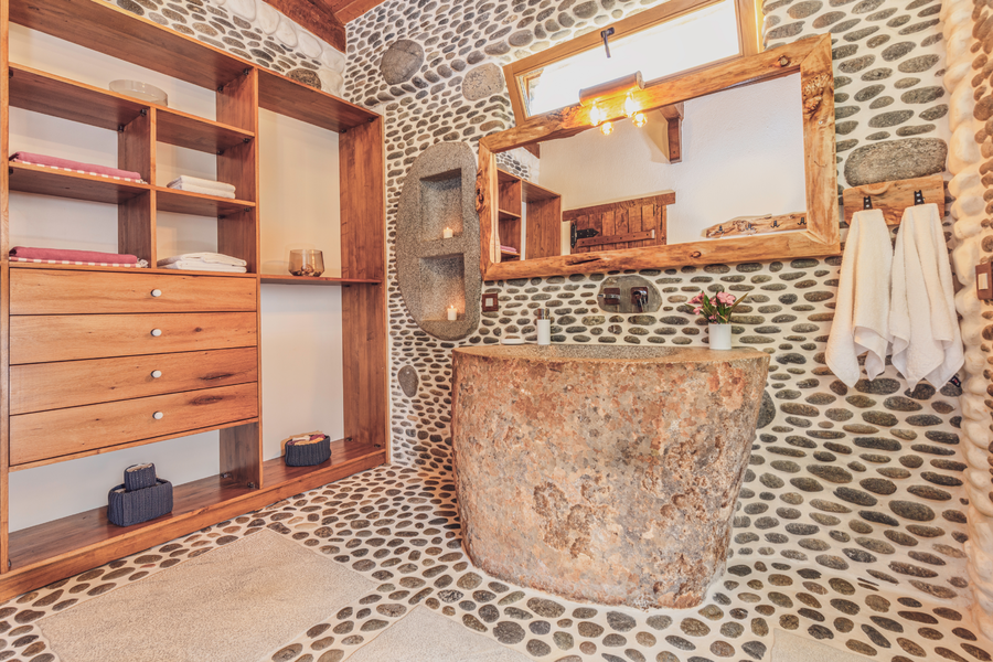 Handcrafted stone bathroom with natural carved sink and pebble walls