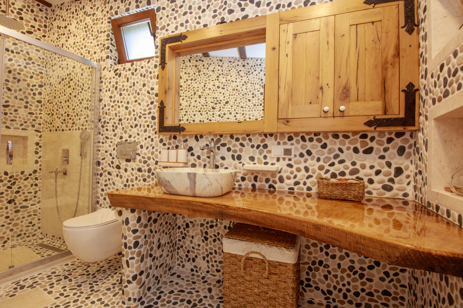 Stone mosaic bathroom with handcrafted wooden cabinetry and marble basin