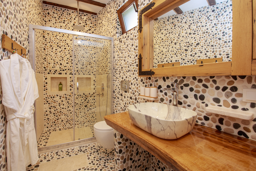 Stone mosaic bathroom with marble vanity and walk-in glass shower