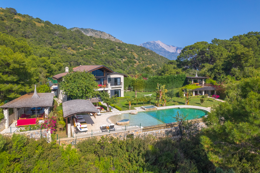 Aerial panorama of Villa Gökçe with stone pool and Mediterranean mountain backdrop