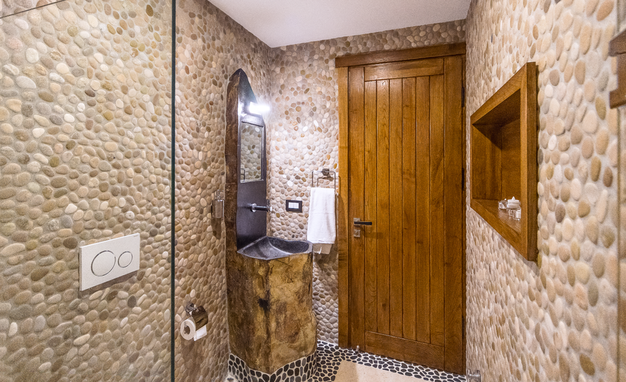 Bathroom with natural stone pebble walls and carved rock basin
