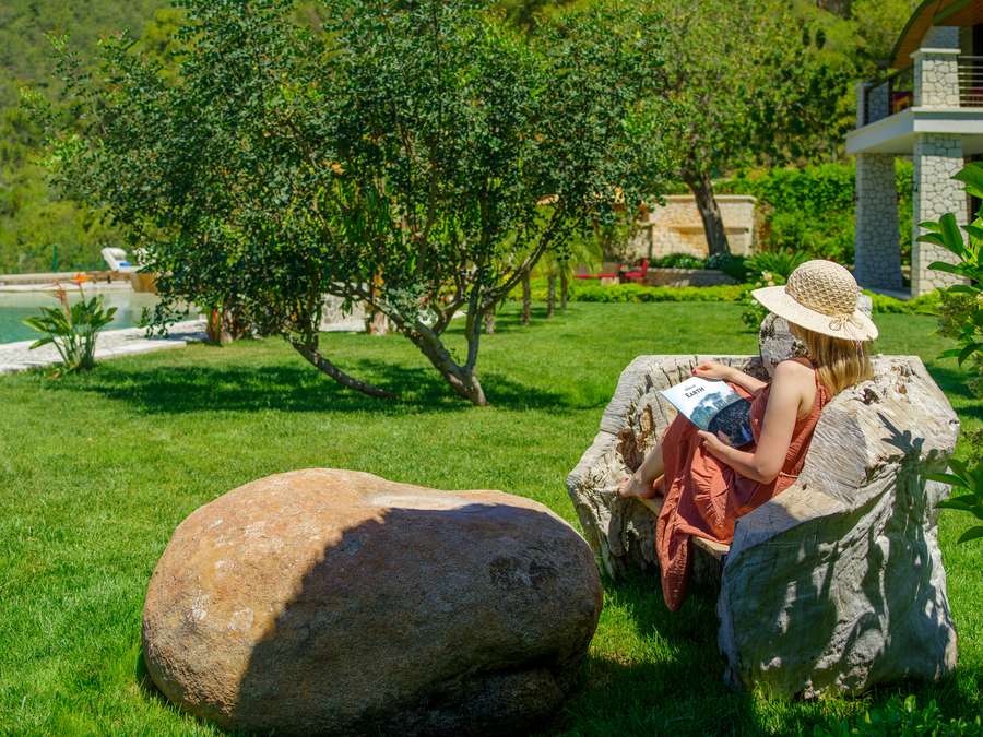 Garden relaxation corner with natural wood seating beside the pool and greenery