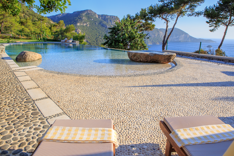 Infinity pool with stone terrace and Mediterranean mountain-sea panorama