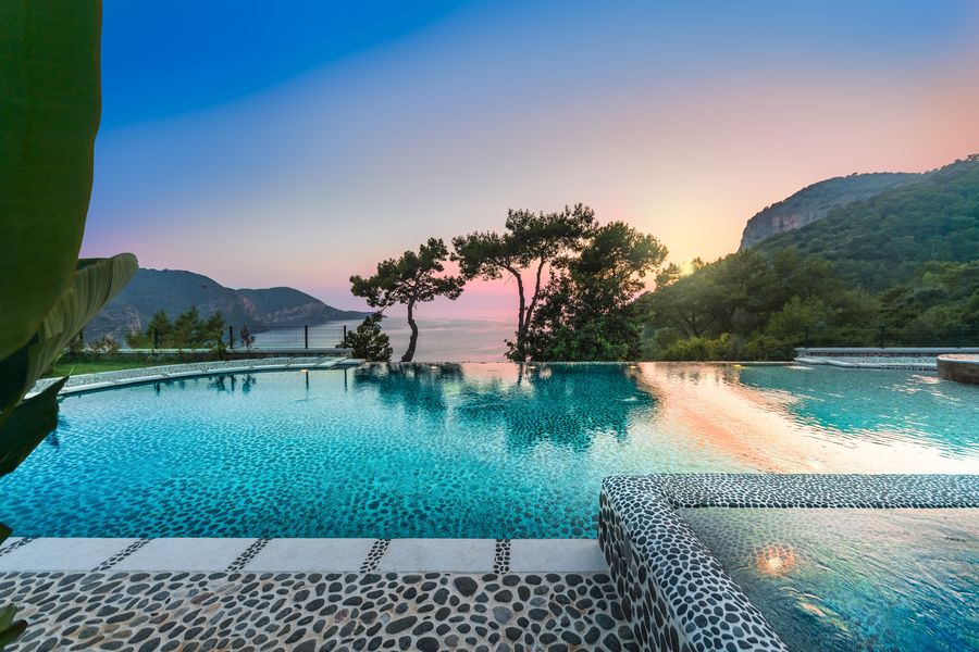 Infinity pool reflecting sunset colors above the Mediterranean bay