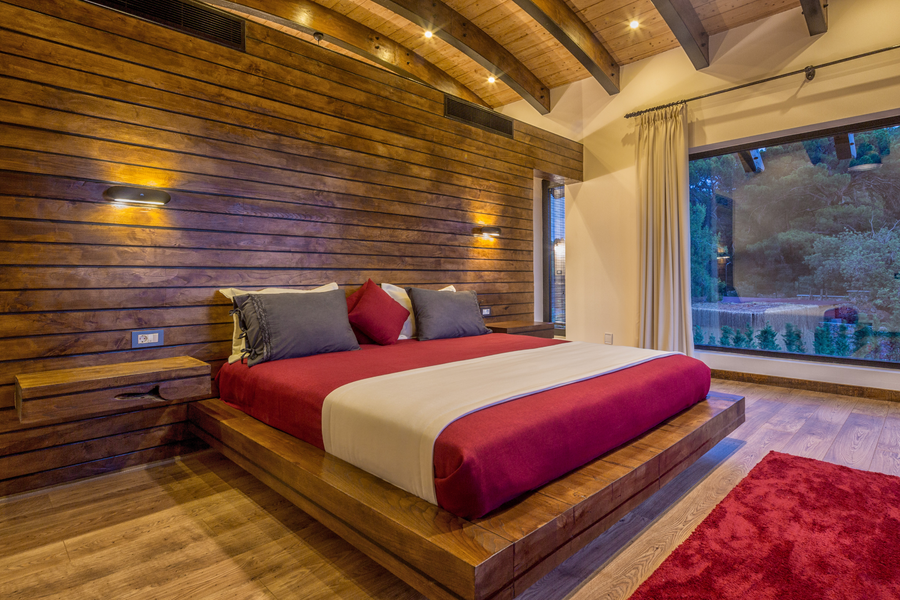 Master bedroom with rustic wood paneling and large landscape window