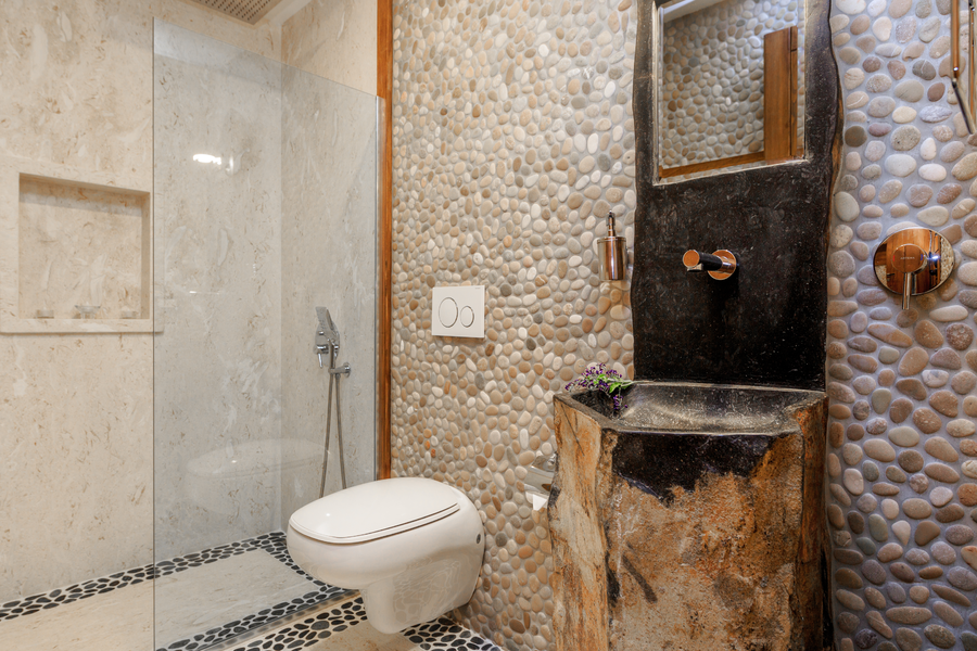 Pebble-stone bathroom with natural carved sink and walk-in shower