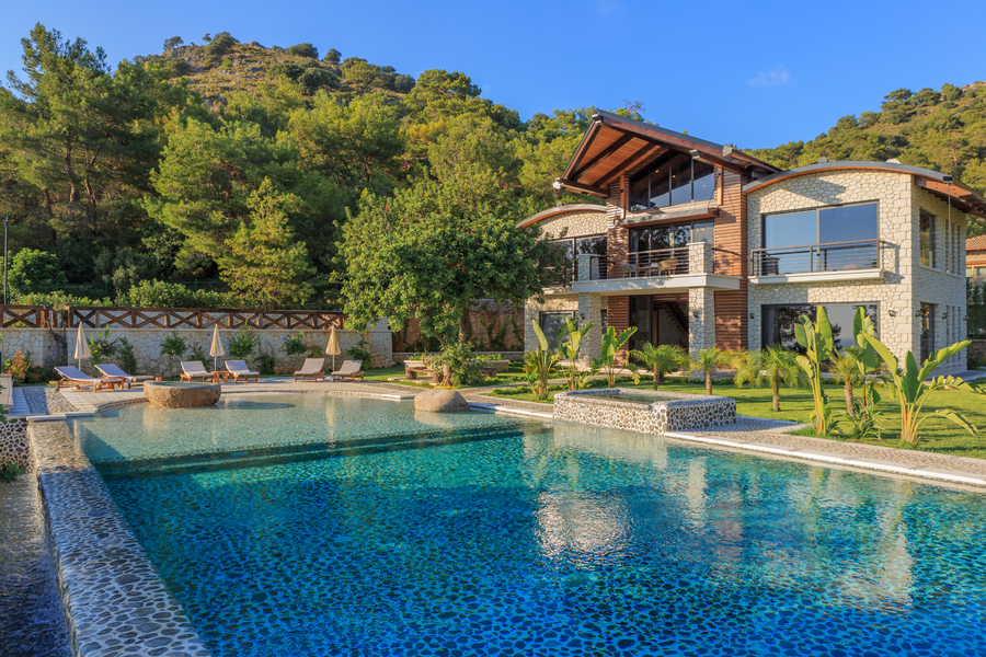 Luxury villa facade overlooking infinity pool and lush Mediterranean gardens