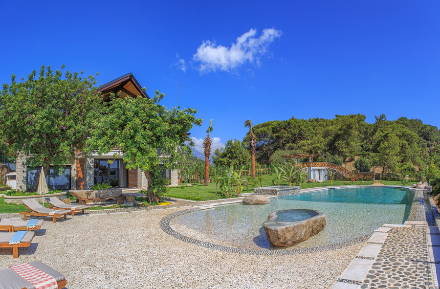 Panoramic pool and garden view with lush greenery and sea backdrop