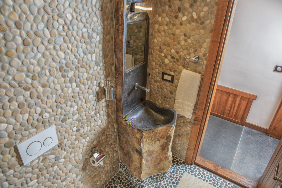 Rustic stone-accent powder room with sculpted natural rock washbasin
