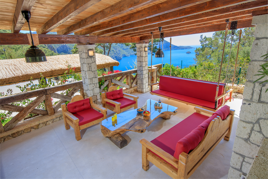 Mediterranean sea-view terrace with wooden lounge seating and red cushions